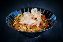 Appetizing noodles in bowl with crisps placed on table