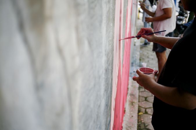 Side view of person painting mural on wall with copy space