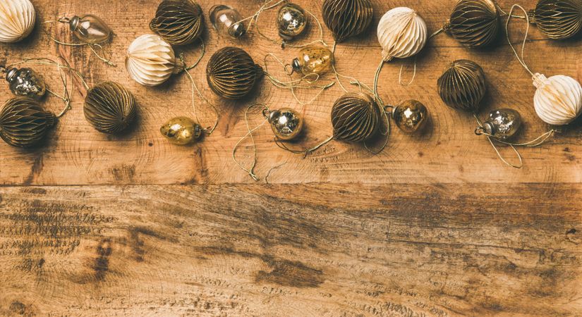 Gold and cream folded tree ornaments, and baubles on wooden board, copy space
