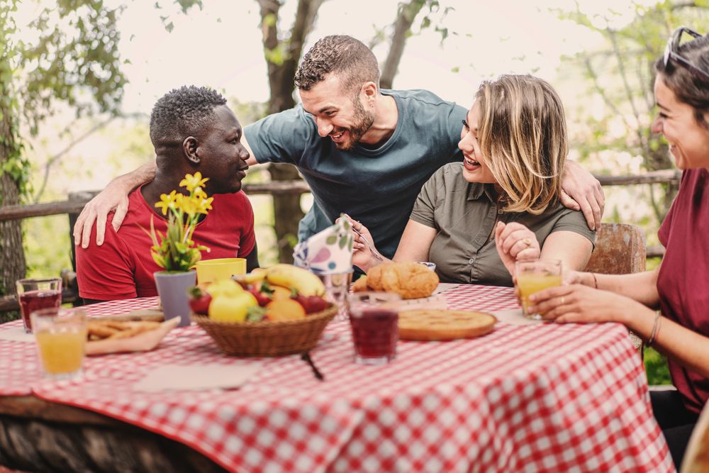 Multi-ethnic group of people gather on farm in the morning for breakfast picnic
