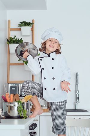 Happy boy in chef uniform with saucepan lid