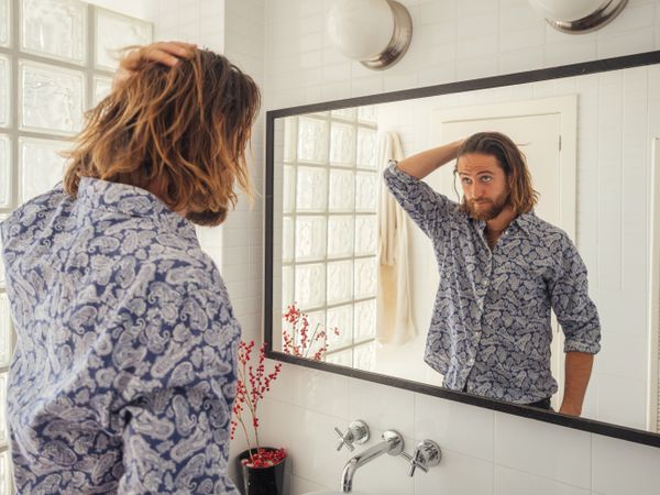 Handsome male checking hairstyle in mirror reflection