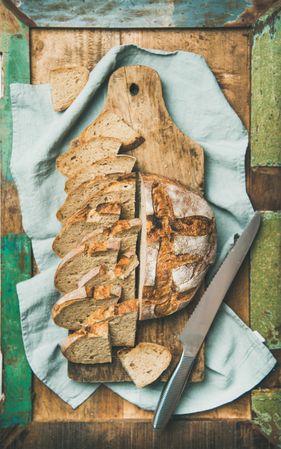 Homemade loaf with slices arranged in line with serrated knife, on linen