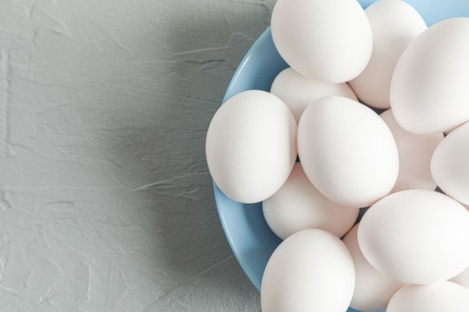 chicken eggs in plate on grey table, space for text and top view
