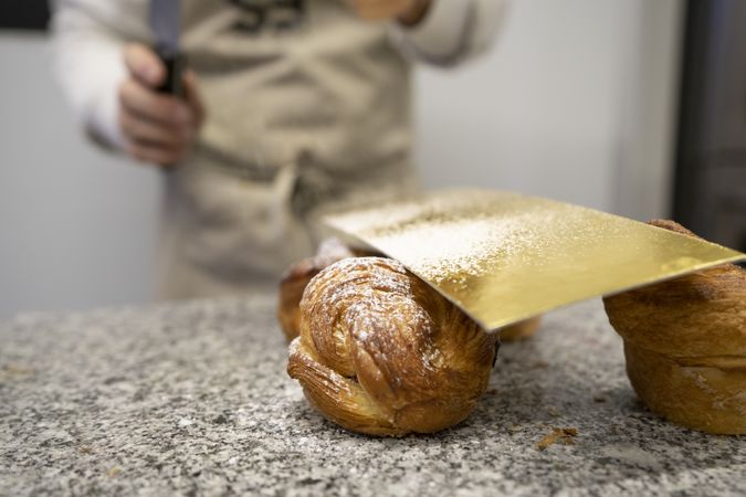 Confectioner decorating freshly baked croissants
