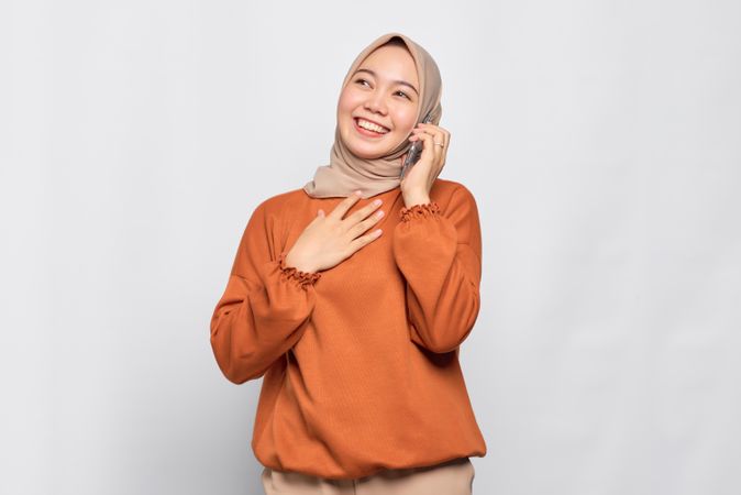 Muslim woman chatting on cell phone with hand on her chest