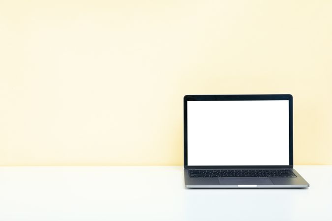 Open laptop with blank mockup screen in cream room with copy space