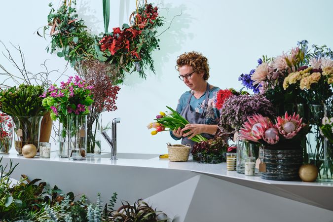 Mature female florist arranging bouquet in shop