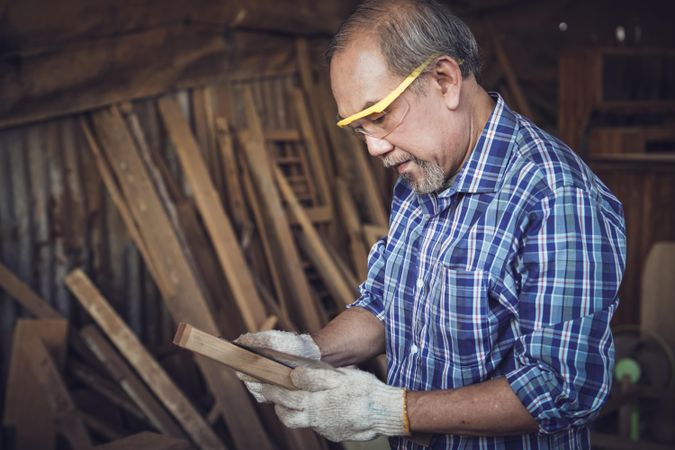 Mature carpenter wearing eye protecting in woodshed