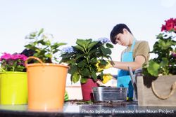 Young smiling teenage boy gardening pots of plants bxA32v