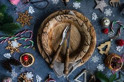 Rustic table setting surrounded by Christmas ornaments, candy canes and fir scattered on marble table