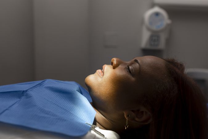 Side view of anesthetized female patient lying back in dental chair