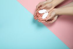 Small lungs being held in two people’s hands on blue and pink background with copy space