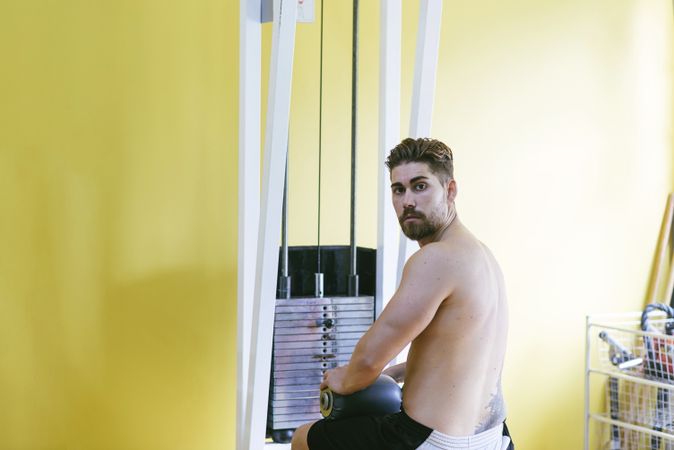 Man turning around while sitting on lat pull down machine, copy space