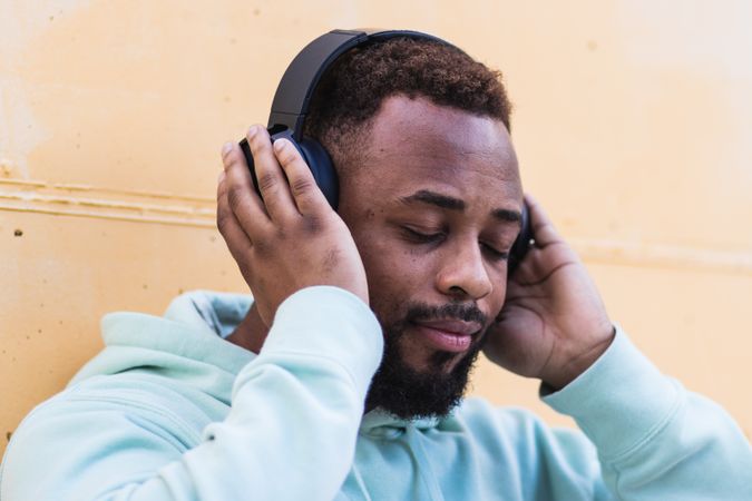 Optimistic Black hipster listening to music with headphones