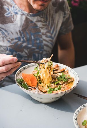 Man eating at Vietnamese restaurant with chopsticks