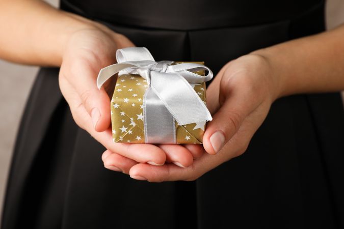 Young woman holding gift box with bow, close up