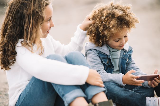 Cheerful kids interacting on nature with smartphone