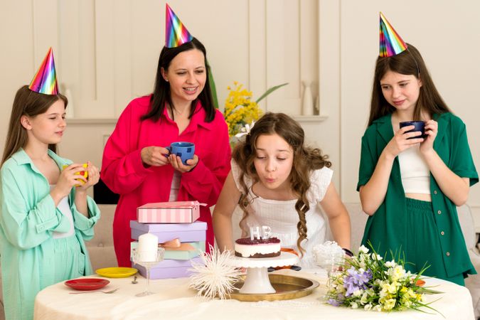 Girl in white dress blows out birthday candles