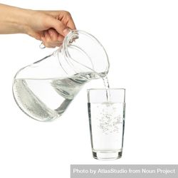 Hand pouring water in glass from pitcher in studio shoot 4mrjzb