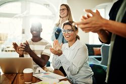 Encouraging group of colleagues applauding in bright office