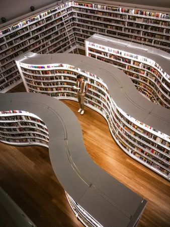 Top view of young man standing between library shelves