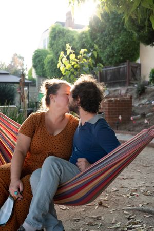 Happy romantic couple kissing in a hammock outdoors in garden