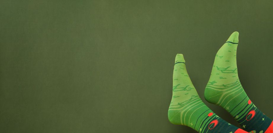 Feets in socks on green background, space for text