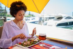 Woman eating a salad in cafe on the pier