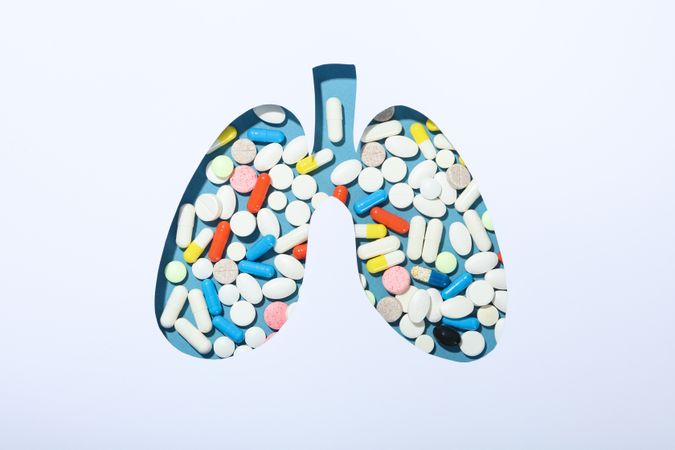 Lung shape cut out of paper with pills underneath