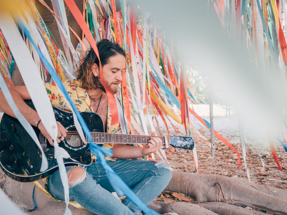 Man sitting under tree playing guitar