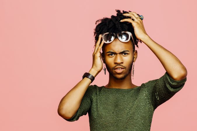 Portrait of a young man holding his head, isolated on pink studio background