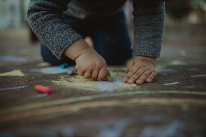 Young child playing with colorful chalk outside