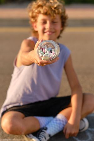Delighted boy with colorful chalks in jar
