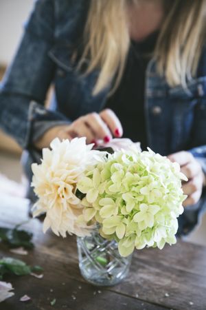 Woman near table with bouquets of blooms in vases