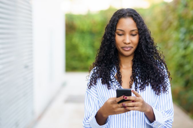 A young woman interacts with her smartphone candidly in a lively urban outdoor setting