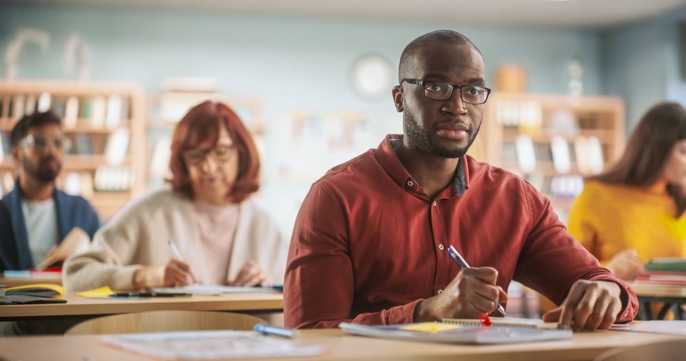 Diverse Mature Students Learning in Classroom, Reading Textbooks and Writing in Notebooks.
