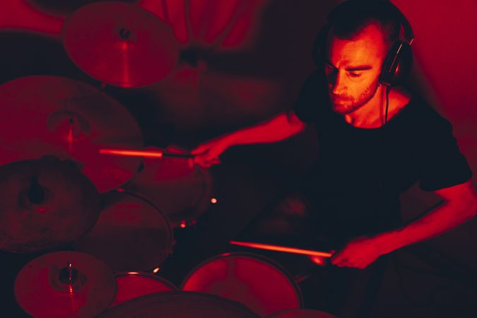 Man with drumsticks playing on drums in redness