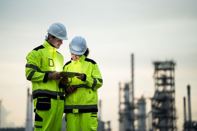 Engineer worker watching work monitor on digital tablet at refinery factory at night