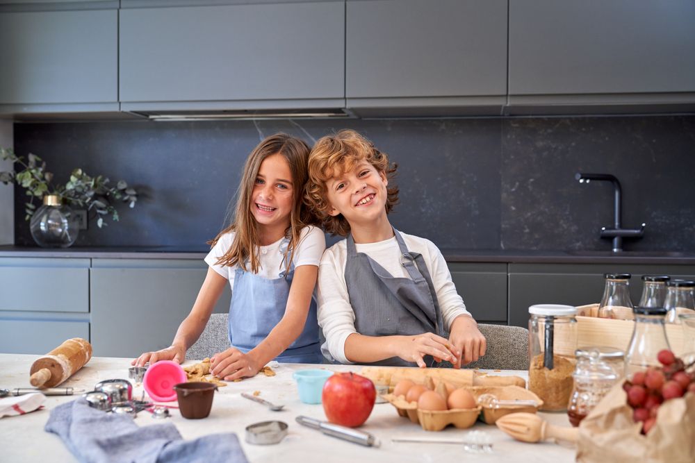Happy children kneading dough for cookies