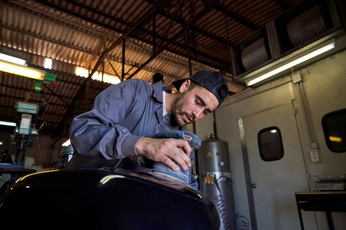 Bearded mechanic repairing motorcycle in garage