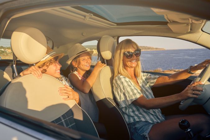 Mother driving a car with the two children in the back seats exp