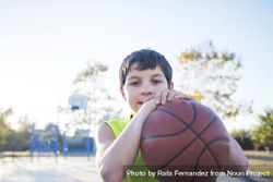 Portrait of a young teen male with sleeveless shirt standing on basketball court while smiling at camera 47gP64