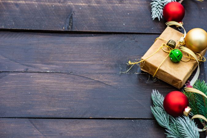 Christmas gift wrapped in brown paper surrounded by baubles