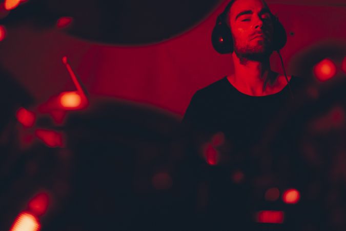 Man with drumsticks playing on drums in redness