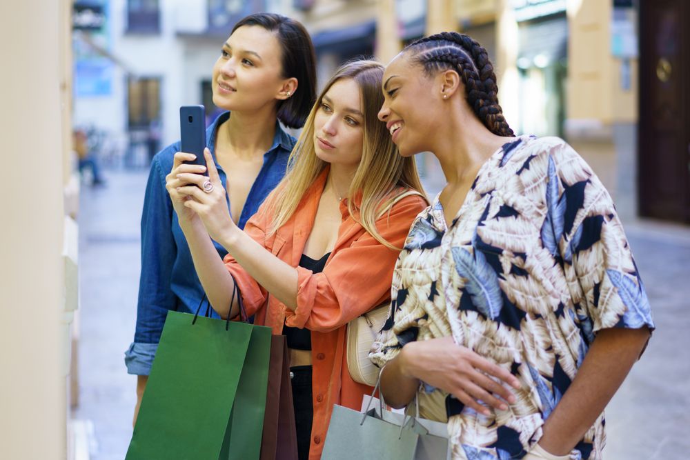 Happy women on shopping trip taking picture of storefront