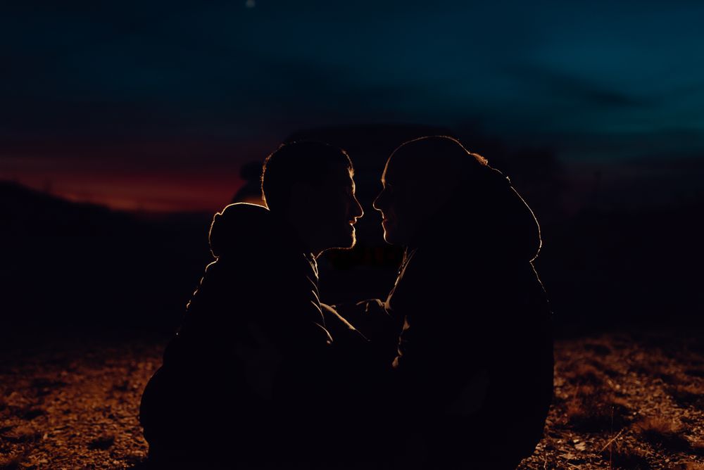 Men hugging and sitting on ground on field at night