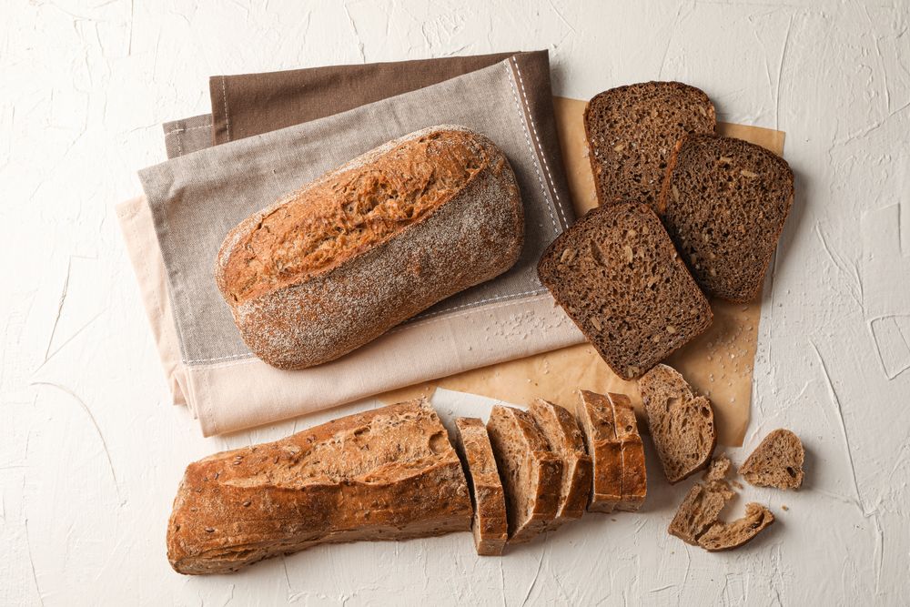 Composition with bakery products, salt and kitchen towel on neutral background, top view and space for text