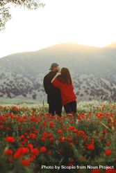 Man and woman standing in red flower field 5kZ1W0