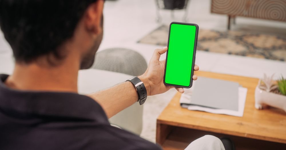 Over the Shoulder Indian Man Using Smartphone with Green Green Screen Screen